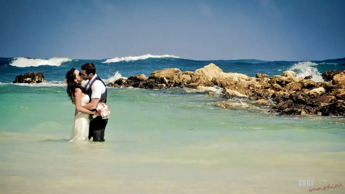 trash the dress photo with a bride and groom kissing while standing in the ocean