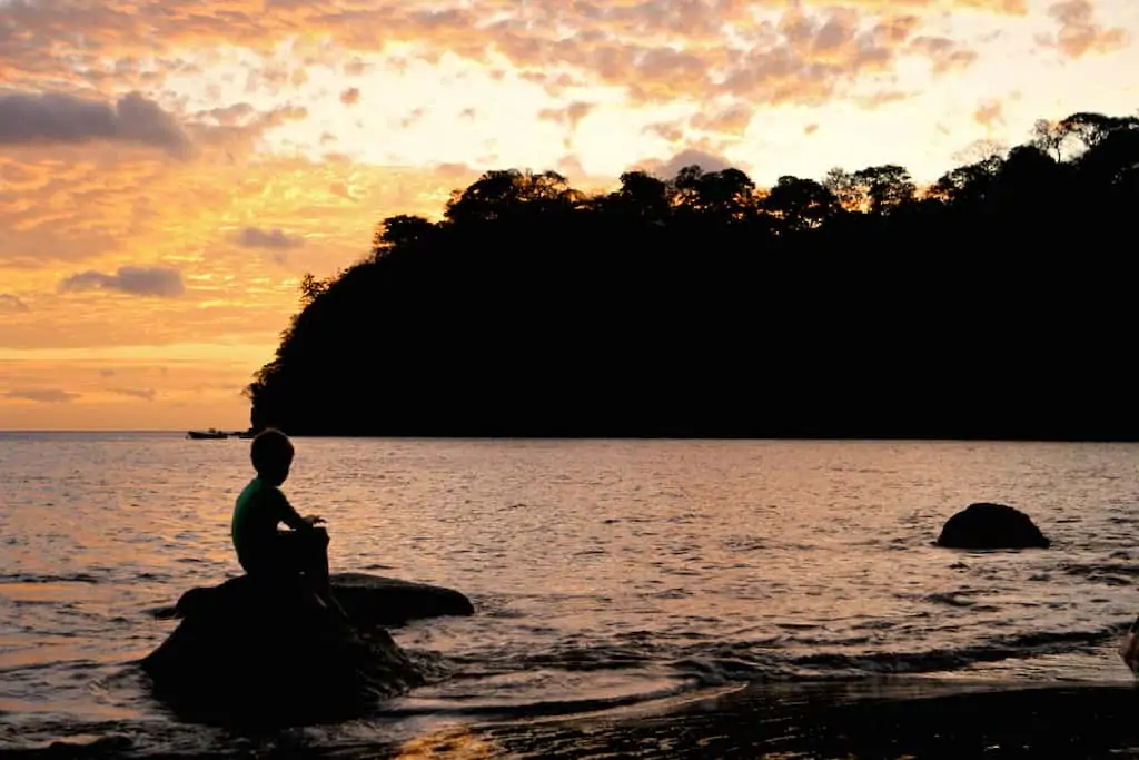 silhouette of boy on rocks on beach in costa rica