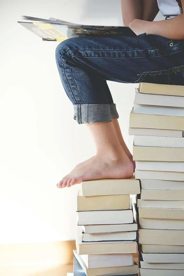 child sitting on stack of books