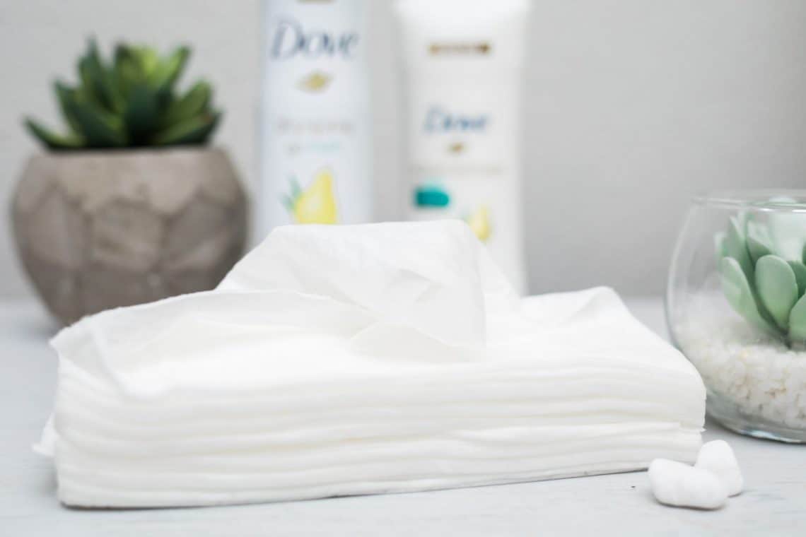 Baby wipes stacked on a gray table with succulents in the back ground they're part of our hot weather beauty tips