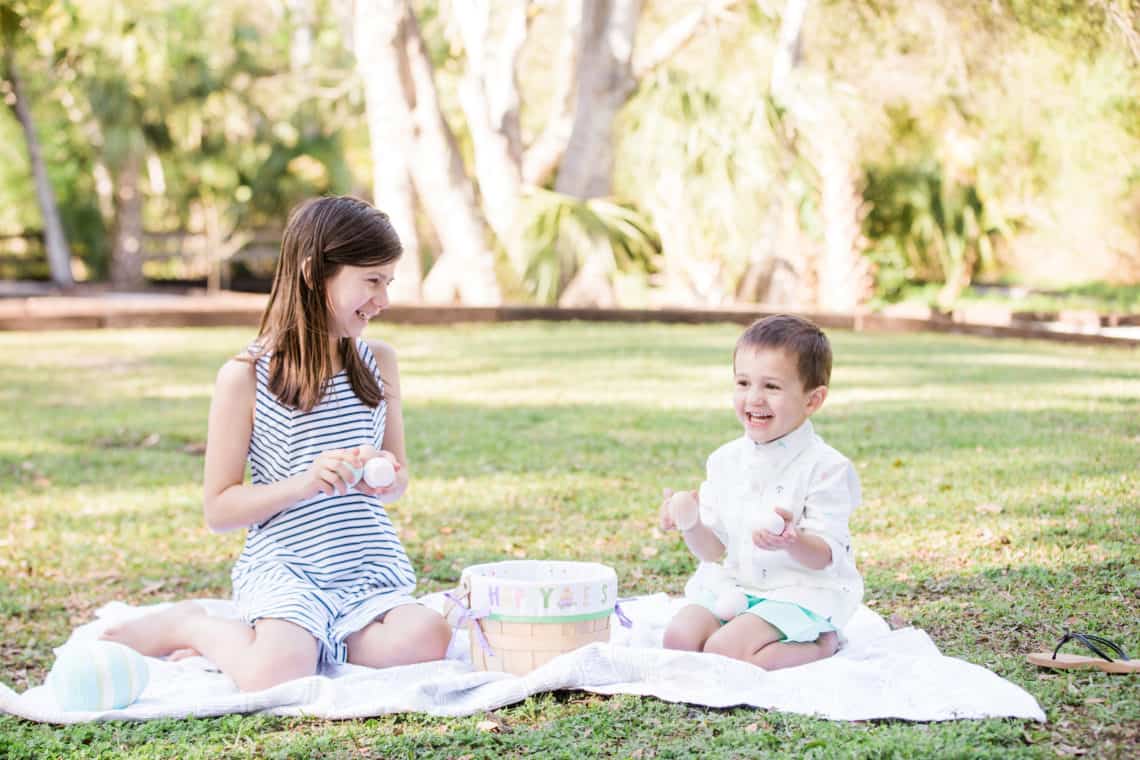 Young children playing with easter eggs on a blanket featuring kids easter outfits they will wear again