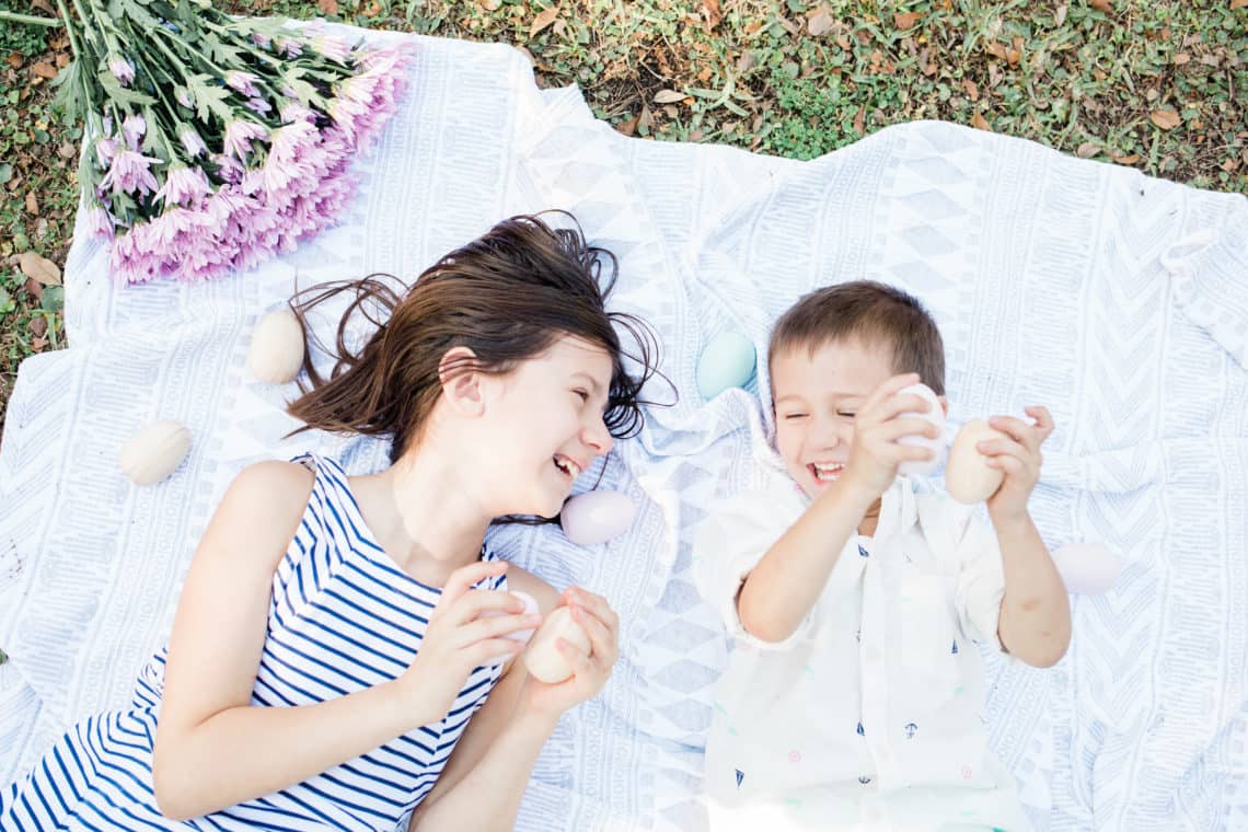 Young children playing with easter eggs on a blanket featuring kids easter outfits they will wear again