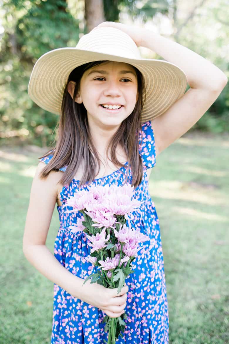 A young girl holds flowers wearing a long flowing kids easter outfits dress. 