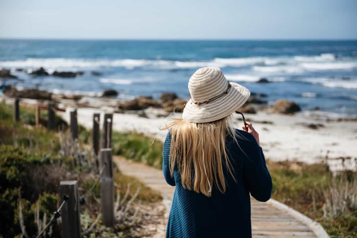 wooden walkway beach woman hat