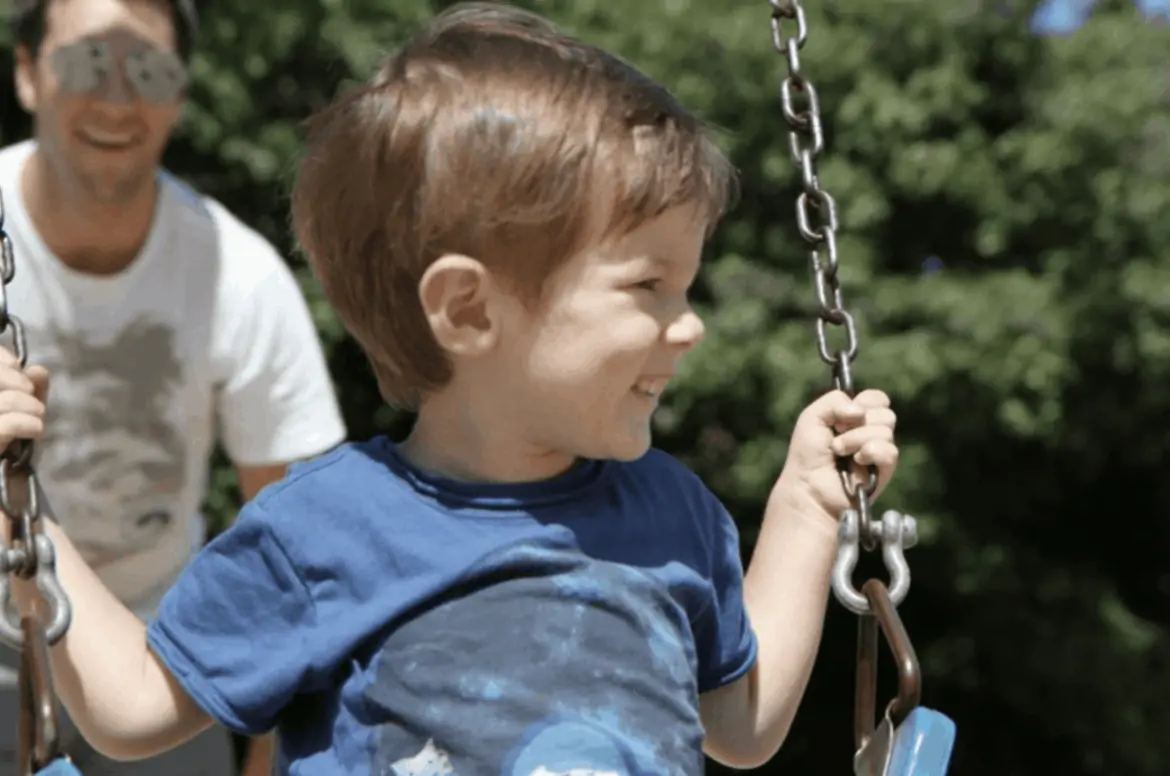 father-pushing-young-boy-on-swing