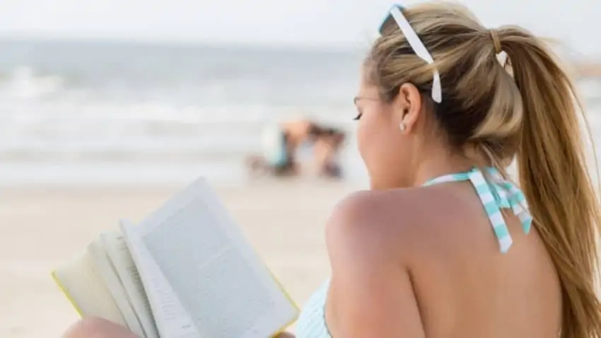 girl reading a book on the beach