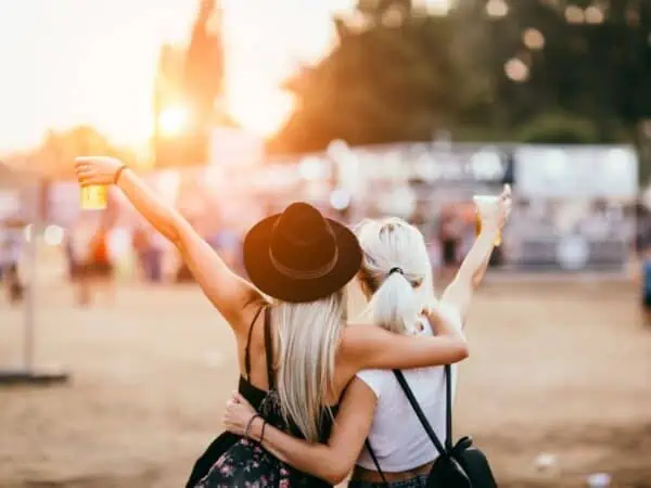 two girls holding up drinks at a festival